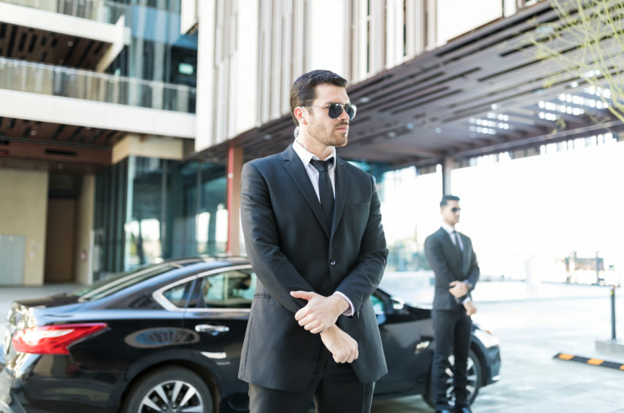 Executive protection services personnel providing secure travel protection for corporate executives outside an office building.
