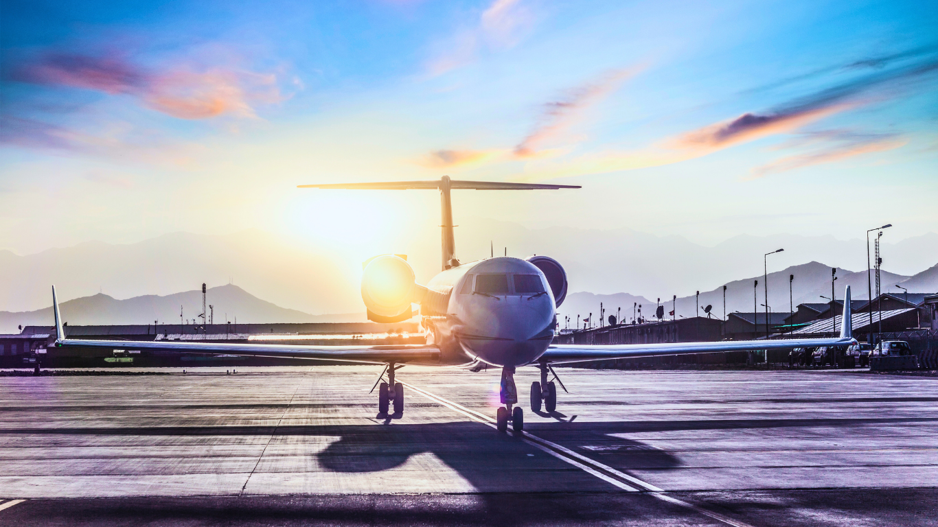 Private jet on runway at airport in European UHNW location with sunlight and mountains