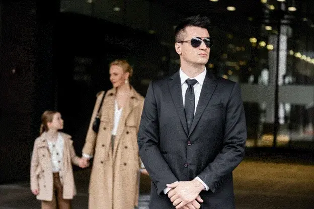 Security professional accompanying a high-net-worth family in a public setting, highlighting the importance of discreet close protection, risk planning and personal safety for UHNW households.